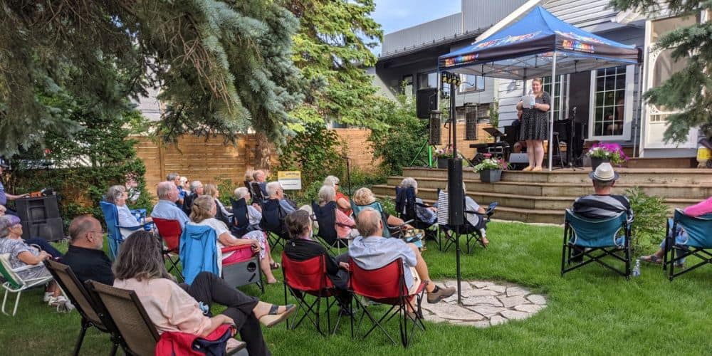 Lot of people sitting in lawn chairs watching a performance on a deck in a historic home in Collingwood. 